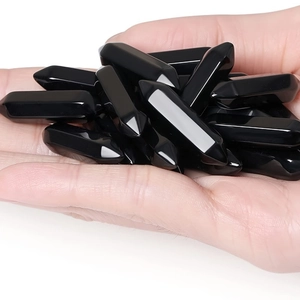 Polished hexagonal black obsidian crystal points held in hand for size visualization