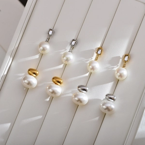Vintage pearl earrings in gold and silver finish on a white textured display stand