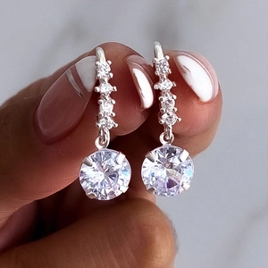 Detail of silver drop earrings with sparkling zircon dangles held by hand