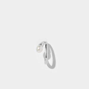 Macro shot of silver ring with minimalist fluid lines and a white pearl on gray backdrop