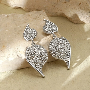 Detail of silver metallic leaf earrings with hollow textures on a natural stone base