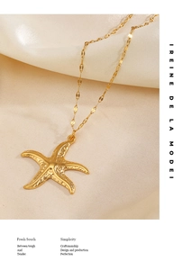 Detailed view of golden starfish pendant with textured hammered finish on silk fabric