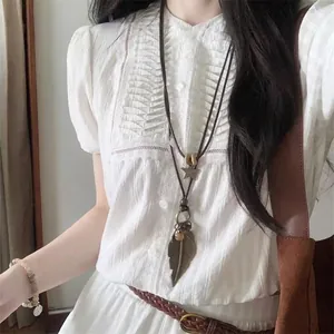 Close-up of bohemian leather cord necklace with bronze star and leaf pendants