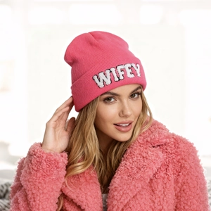 Détail d'un bonnet en maille rose avec broderie blanche WIFEY et texture côtelée
