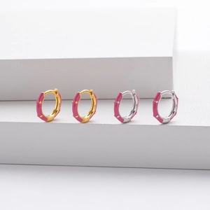 Detailed view of gold and silver huggie earrings with pink enamel on geometric blocks