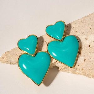 Dettaglio di orecchini a cuore in oro 18k con smalto blu su pietra naturale