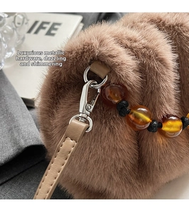 Close-up of brown plush bucket bag with silver hardware and amber resin beads