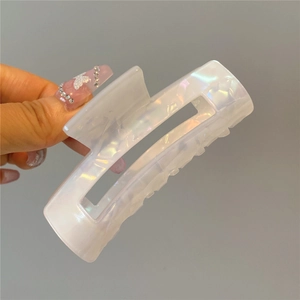 Macro detail of a white pearlescent acetate hair claw clip with geometric hollow design