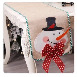 Detail of Christmas snowman linen table runner with a red polka dot bow and holiday motifs
