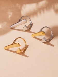 Detailed view of minimalist geometric open rings in gold and silver with elegant shadows