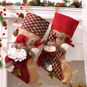 Set mit 2 Weihnachtssocken mit Nikolaus und Schneemann an einem festlichen weißen Kamin