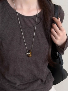 Macro detail of brown tiger eye beads and silver pony pendant on a long necklace