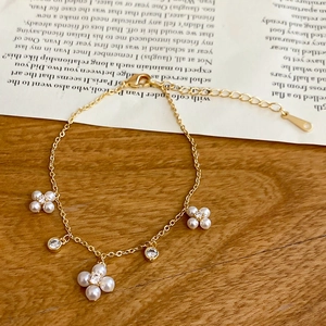 Close-up of gold chain bracelet with pearl flower charms and sparkling zircon accents