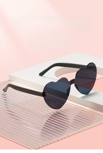 Detail shot of heart-shaped sunglasses with black frames on a stylish pink display stand
