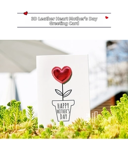 Detail showing white card with red leather heart and Mother's Day message on plant background
