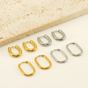 Minimalist oval hoop earrings in gold and silver finish on neutral stone background