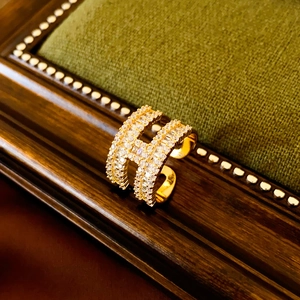 Close-up of gold-plated H-shaped ring with inlaid cubic zirconia on a velvet display