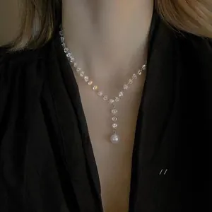 Detail view of a Y-shaped crystal beaded necklace with a white round pearl pendant
