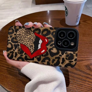 Leopard print iPhone case with red lips design held by a model on a cafe table background