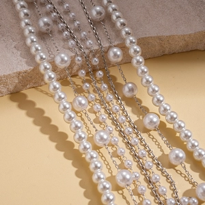 Detail of multilayered faux pearl necklace with silver chain on stone background
