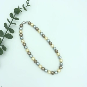 Detail of colorful pearl necklace with cream, grey, brown beads and metal clasp