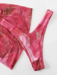 Detailed close-up of rose red bikini fabric with gold marble texture print