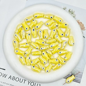 Macro shot of yellow fish-shaped ceramic beads for DIY jewelry with threading detail