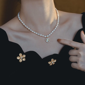 Elegante collana di perle con ciondolo a doppia stella e bordo dorato su modella