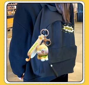 Detail von Shiba Inu Schlüsselanhänger mit gelber Figur und Band auf schwarzem Rucksack