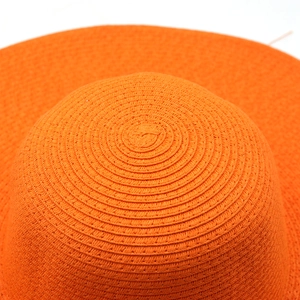 Detailed macro view of the spiral woven texture on a bright orange straw sun hat