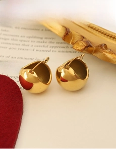 Detail view of gold U-shaped minimalist earrings on vintage background with lever back closure