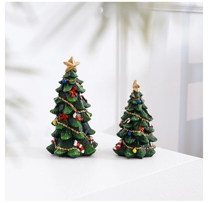 Close-up of mini resin Christmas trees with gold stars and festive red bows decoration