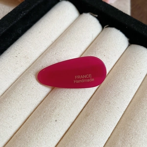 Gros plan sur une pince à cheveux goutte en acrylique rose foncé avec texte doré France