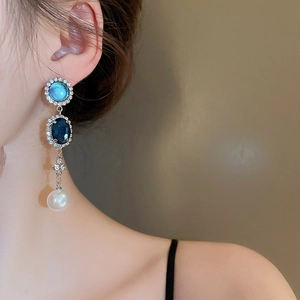 Détail de boucles d'oreilles pendantes françaises avec pierres bleues et perles