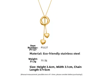 Detail view of gold stainless steel necklace with round pendant and heart charms