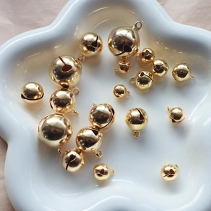 Polished gold round bells in white ceramic dish for DIY jewelry and pet collar crafts