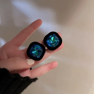 Gros plan détaillé sur boucle d'oreille rétro avec pierre carrée verte et velours noir