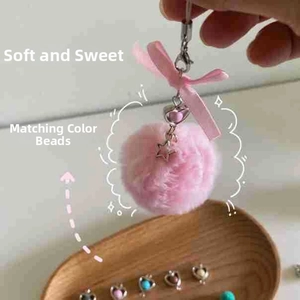 Detailed close-up of a pink plush pompom keychain with silk bow and star charm