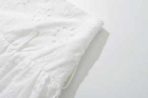 Close-up of intricate white lace embroidery and texture on the low-waist mini skirt