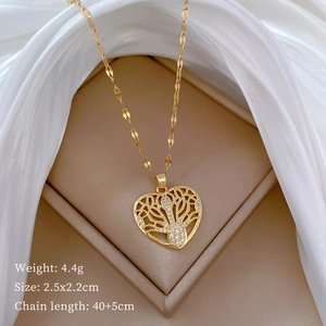 Close-up of golden heart pendant with tree of life and crystals on white silk