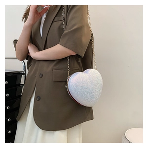 Detail of heart-shaped crossbody bag with glittering sequins and golden chain strap