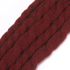 Close-up of red knitted glove showing detailed cable knit texture and soft acrylic yarn