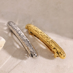 Close-up of gold and silver stainless steel hair clips with hammered liquid metal texture