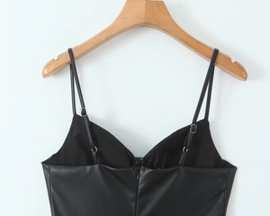 Detalle de camisola negra en cuero sintético con cremallera y tirantes ajustables