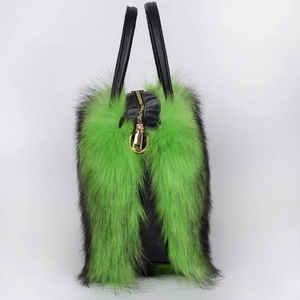 Detail of green faux fur tote bag with gold metal zipper and black leather handles