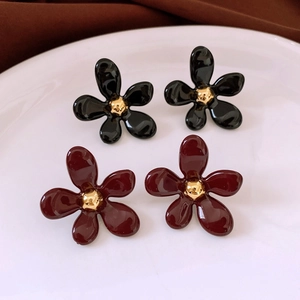 Détail des boucles d'oreilles fleurs à cinq pétales noires et bordeaux au cœur doré