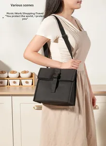 Detail of insulated lunch bag with buckle closure and adjustable strap on a kitchen counter