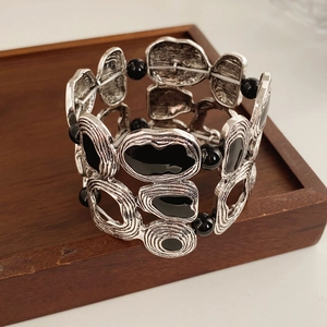 Close-up of vintage geometric silver alloy bracelet with black enamel on a wooden tray
