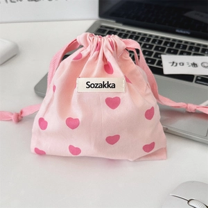 Detailed view of pink drawstring bag with heart patterns and woven brand label