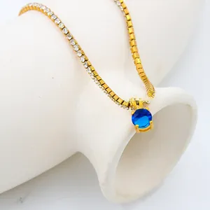 Detailed close-up of a 18K gold plated necklace with a round faceted blue zircon pendant